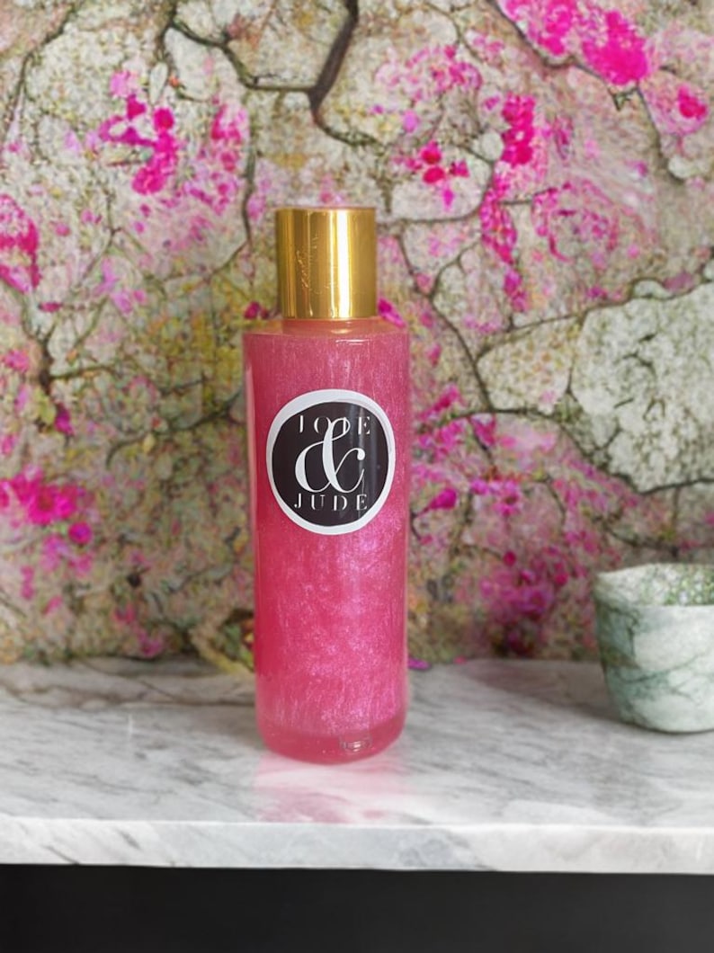 May include: A pink bottle with a gold lid and a black and white label that says "Love & Jude". The bottle is filled with a pink liquid with glitter.