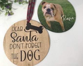 May include: Two round wooden ornaments with red and black plaid ribbon. One ornament has a photo of a bulldog with the name "Rosie" written on it. The other ornament has the text "Dear Santa Don't Forget The Dog" with a bone and paw print.