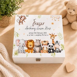 May include: White wooden keepsake box with a hinged lid, featuring a charming jungle animal design. The box is personalized with the name "Fraser" and birth details. Adorable illustrations of a monkey, elephant, lion, hippo, tiger, panda, giraffe, and zebra adorn the box.
