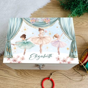 May include: A white wooden keepsake box featuring a watercolor illustration of three ballerinas in tutus. The box is decorated with light blue curtains, floral accents, and the name "Elizabeth" in script.