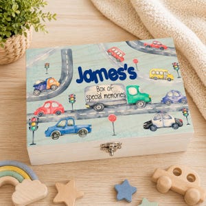 Può includere: Un cofanetto in legno con sfondo azzurro chiaro e una scena stradale fantasiosa con varie auto, camion e semafori colorati. Il cofanetto è personalizzato con il nome "James's" e il testo "Box of special memories".