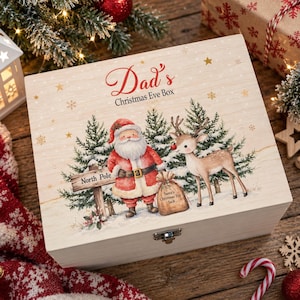 Könnte beinhalten: Eine rechteckige Holzkiste mit Klappdeckel, die eine gedruckte Illustration des Weihnachtsmanns und eines Rentiers in einem verschneiten Wald zeigt. Der Text "Dad's Christmas Eve Box" steht oben, "North Pole" auf einem Schild und "Santa's Christmas Toy Sack" auf einem Sack.
