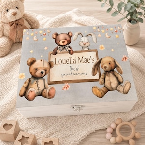 Puede incluir: Caja de recuerdos de madera blanca con tapa gris claro adornada con osos de peluche, un conejito, estrellas y lunas. La tapa tiene el texto "Louella Mae's Box of special memories". La caja se asegura con un cierre plateado.