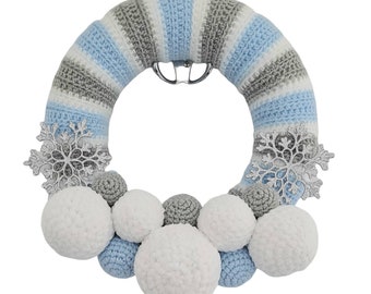 May include: A blue and gray crocheted wreath with white and gray crocheted balls and silver snowflake ornaments.