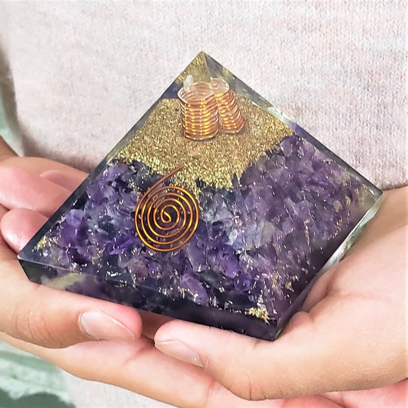 May include: Amethyst crystal pyramid with a copper wire spiral and gold glitter. The pyramid is approximately 3 inches tall.