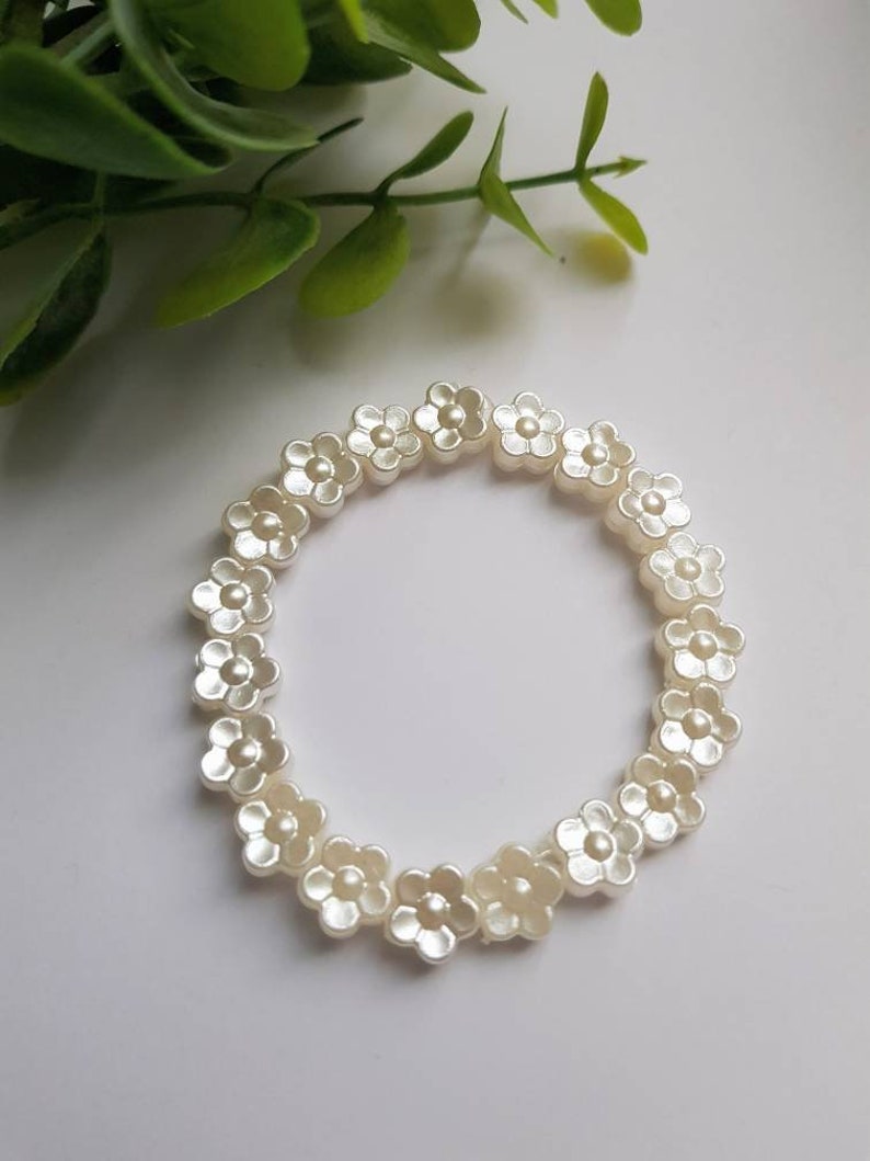 May include: A white flower bracelet made of plastic beads. Each bead is shaped like a flower with five petals.