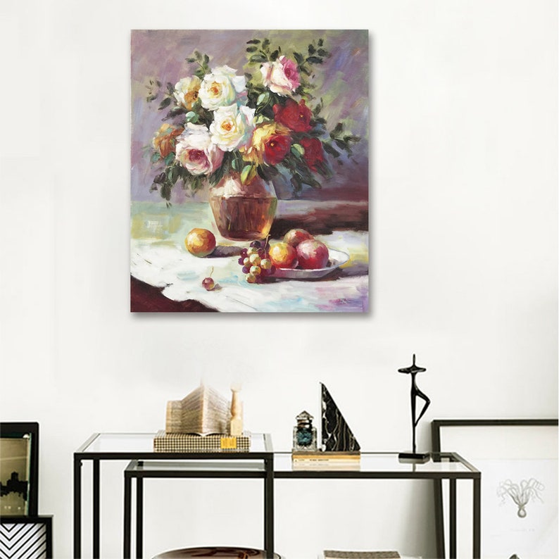 May include: A still life painting of a vase filled with white, yellow, and red roses. The vase is brown and sits on a white tablecloth with a bowl of fruit and grapes.