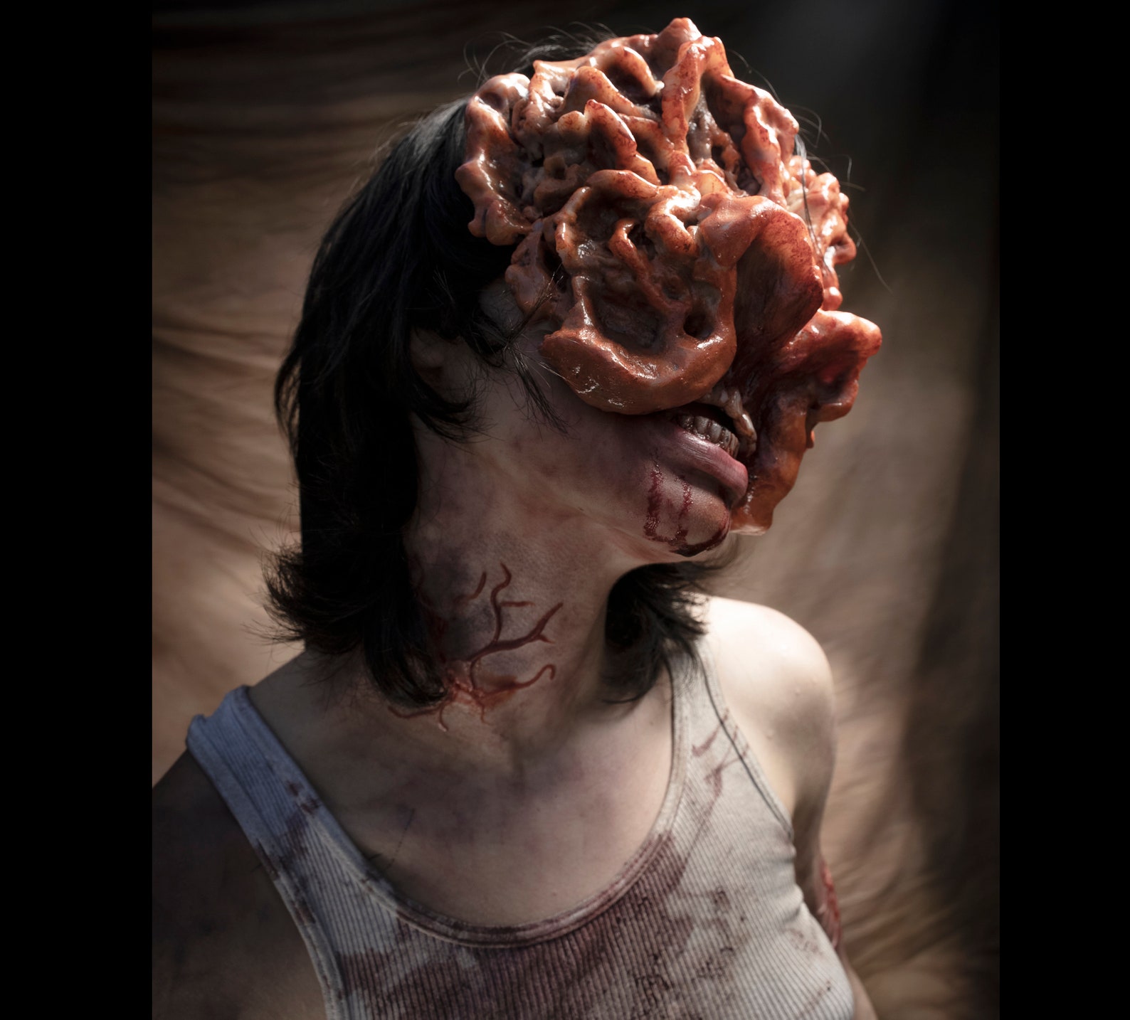 A woman wearing a bloody tank top with infected marks on her neck and chin. Her face is covered with a clicker mask from The Last of Us.