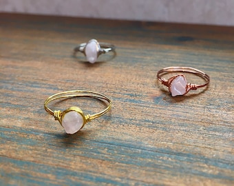 May include: Three wire-wrapped rings with pink quartz stones. The rings are made with gold, silver, and copper wire.