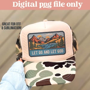 May include: A trucker hat with a beige front panel and a camouflage print on the brim and back. The hat features a rectangular patch with a mountain and lake scene and the text "LET GO AND LET GOD".