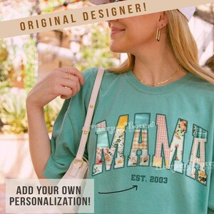 Könnte beinhalten: Ein blaues T-Shirt mit einem Patchwork-Design, das "MAMA" in bunten Stoffen buchstabiert. Das Shirt hat einen schwarzen Pfeil, der auf den Text "EST. 2003" zeigt, und den Text "harper house THREE SIXTEEN" unten.