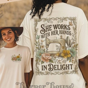 May include: Cream-colored t-shirt featuring a floral design with a butterfly and the text "She Works With Her Hands In Delight" and "Proverbs 31:13". The shirt also has a vintage sewing machine graphic. The brand name "Harper House Three Sixteen" is at the bottom.