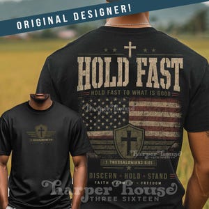 May include: Black t-shirt with a distressed American flag design and the words "HOLD FAST" in a bold font. The shirt also features a cross and the text "1 Thessalonians 5:21". The design includes the words "DISCERN HOLD STAND" and "FAITH FAMILY FREEDOM".