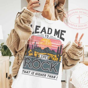 May include: White t-shirt with a sunset graphic and the text "Lead Me To The Rock That Is Higher Than I".