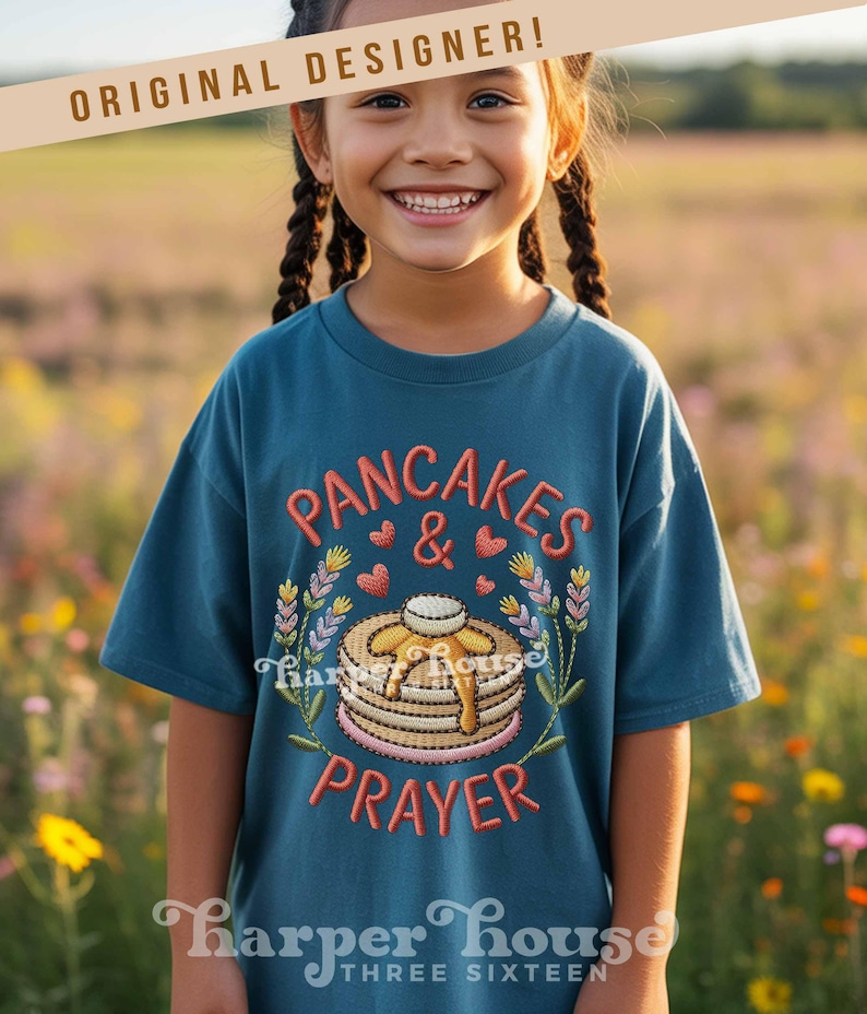 May include: Teal t-shirt with embroidered text and design. The design features the words "PANCAKES & PRAYER" with a stack of pancakes, hearts, and floral elements. The shirt is from Harper House Three Sixteen.