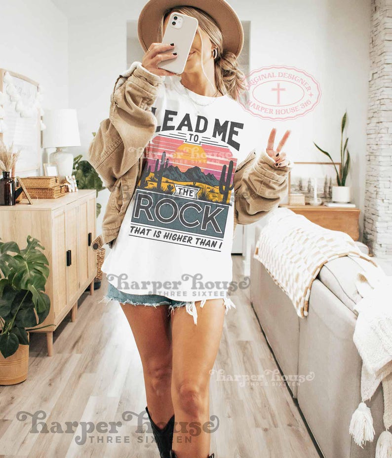May include: White t-shirt with a sunset graphic and the text "Lead Me To The Rock That Is Higher Than I".