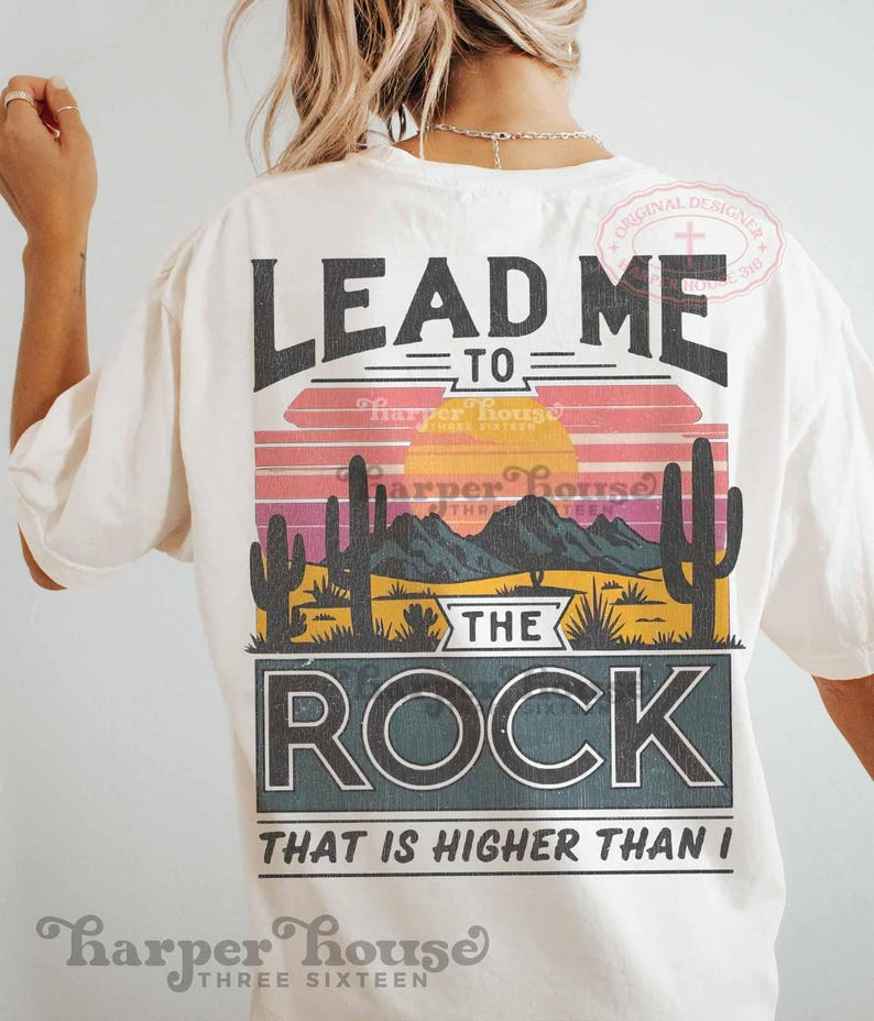 May include: White t-shirt with a vintage-style graphic that says "Lead me to the rock that is higher than I". The graphic features a sunset, mountains, and cacti.