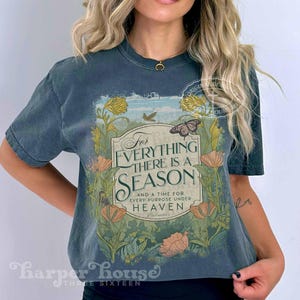 May include: A dark blue t-shirt with a vintage floral design and the text "For Everything There Is A Season And A Time For Every Purpose Under Heaven".
