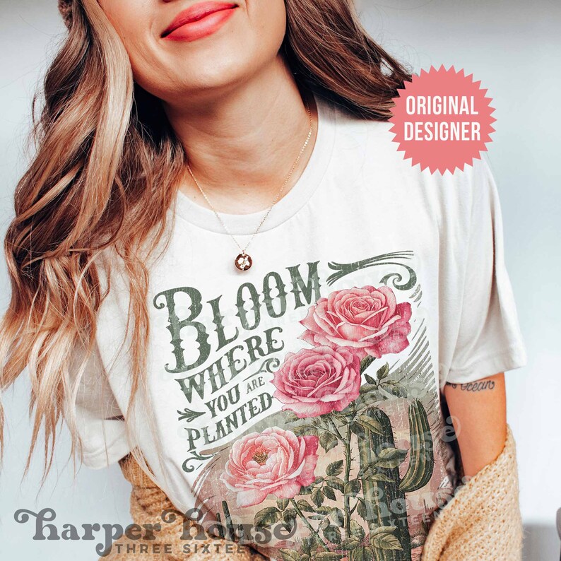 May include: White t-shirt with a vintage-style graphic featuring pink roses, a cactus, and the text "Bloom Where You Are Planted".
