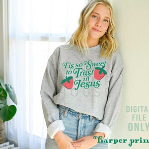 May include: A gray sweatshirt with a strawberry graphic and the text "Tis so Sweet to Trust in Jesus".