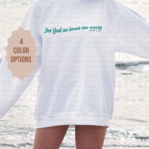 May include: White sweatshirt with the text "For God so loved the world" in green lettering and the scripture reference "John 3:16" in smaller font below.