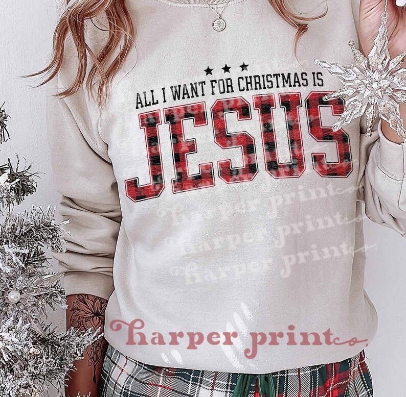 May include: A white sweatshirt with the text "ALL I WANT FOR CHRISTMAS IS JESUS" printed in red and black buffalo plaid.