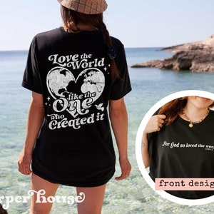 May include: Black t-shirt with a white graphic print of a heart with a world map inside and the text "Love the World like the One who Created it". The front of the shirt has the text "for God so loved the world" in white.