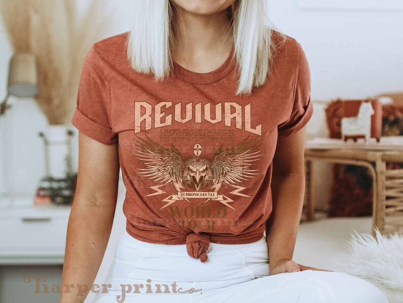 May include: A rust-colored t-shirt with a graphic design of an eagle with wings spread, a cross, and the text "REVIVAL 2 CHRONICLES 7:14 WORLD TOUR".