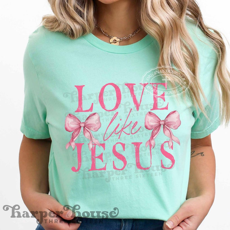 K&ouml;nnte beinhalten: Hellgr&uuml;nes T-Shirt mit dem pinkfarbenen Schriftzug "LOVE like JESUS" und zwei rosa Schleifen. Das T-Shirt hat einen Rundhalsausschnitt und kurze &Auml;rmel. Der Markenname "Harper House" ist unten aufgedruckt.