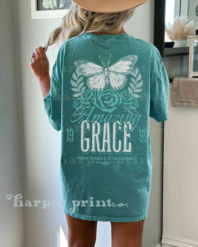 Pu&ograve; includere: Una maglietta blu turchese con una farfalla bianca, rose e il testo "Amazing Grace" con gli anni 19 e 99 su entrambi i lati. Il testo "How Sweet The Sound" &egrave; sotto il testo principale.