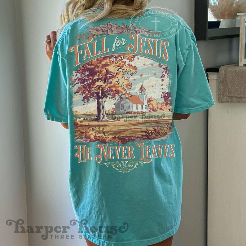 May include: A turquoise t-shirt with the words "FALL for JESUS" and "HE NEVER LEAVES" in an orange script. The back of the shirt features a graphic of a church, a tree with autumn leaves, and the text "Harper House Three Sixteen."