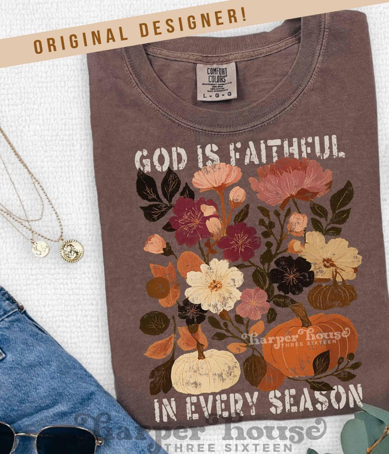 May include: A brown Comfort Colors t-shirt with the text "GOD IS FAITHFUL IN EVERY SEASON." The shirt features a floral and pumpkin design in shades of cream, orange, burgundy, and brown. The words "ORIGINAL DESIGNER!" are at the top.
