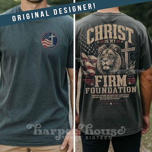 May include: Dark gray t-shirt with a distressed look. The front features a circular design with a cross, American flag, and text. The back displays a lion, cross, flag, and the words "Christ is my Firm Foundation."