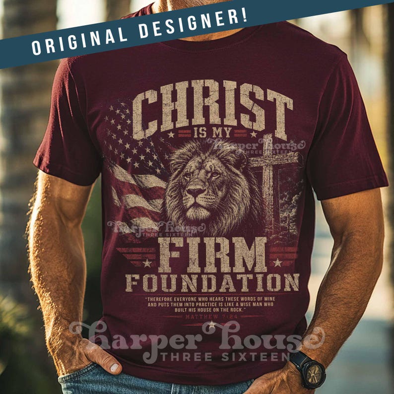 May include: Burgundy t-shirt with a distressed design featuring a lion, American flag, and cross. The text reads "Christ is my Firm Foundation" and a Bible verse. The shirt has the words "Original Designer!" at the top.