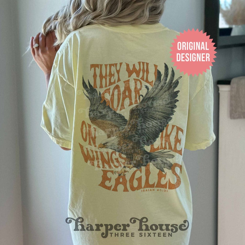 May include: A yellow t-shirt with a vintage-style graphic of an eagle with the text "They Will Soar On Wings Like Eagles Isaiah 40:31" printed on the back. The shirt also has the text "Harper House Three Sixteen" printed on the bottom.
