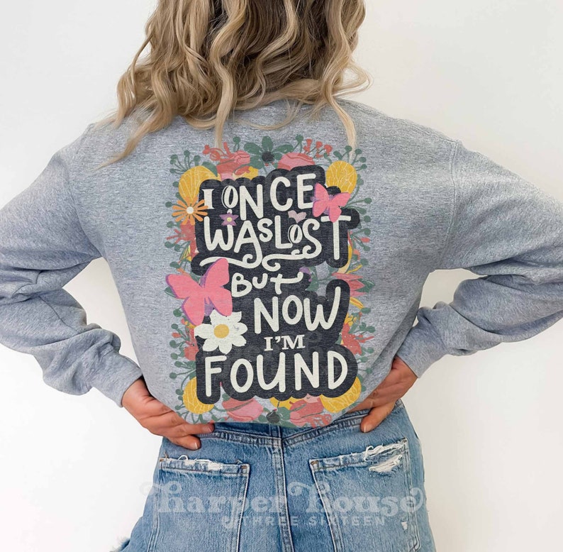 May include: Gray sweatshirt with a floral design and the text "I once was lost but now I'm found".