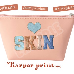 May include: Pink cosmetic bag with a heart and the word "SKIN" in colorful embroidered letters. The bag has a zipper closure and a small silver pull tab. The text "harper print co." is printed in brown below the bag.