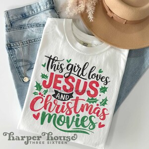 May include: White t-shirt with a red and green graphic that says "This girl loves Jesus and Christmas movies". The graphic has a distressed look and is surrounded by green holly leaves.