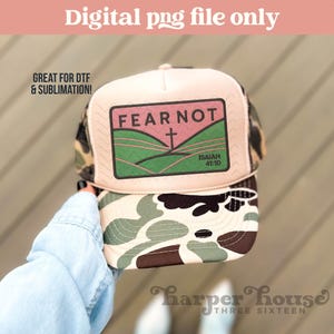 Könnte beinhalten: Eine Trucker-Cap mit Camouflage-Schirm und Seitenteilen sowie einem hellrosa Vorderteil. Ein rechteckiger Aufnäher zeigt eine Landschaftsgrafik mit dem Text FEAR NOT und ISAIAH 41:10 sowie einem Kreuzsymbol.