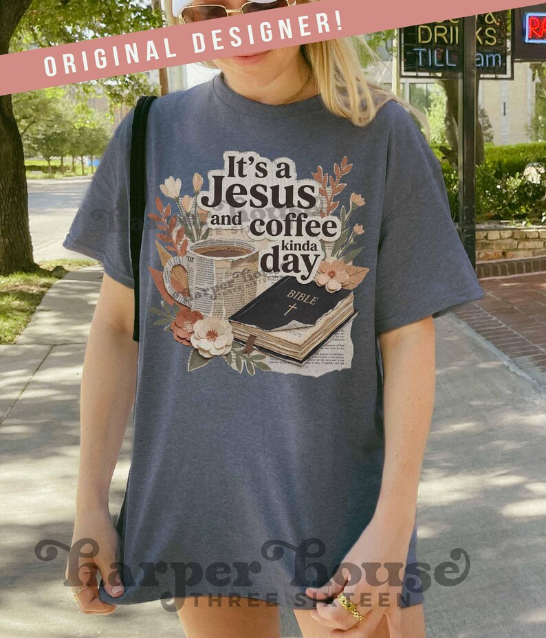 May include: A dark gray t-shirt with the text "It's a Jesus and coffee kinda day" and a graphic of a coffee cup, flowers, and a Bible. The shirt has short sleeves and a relaxed fit. The words "ORIGINAL DESIGNER!" are printed on a pink banner.