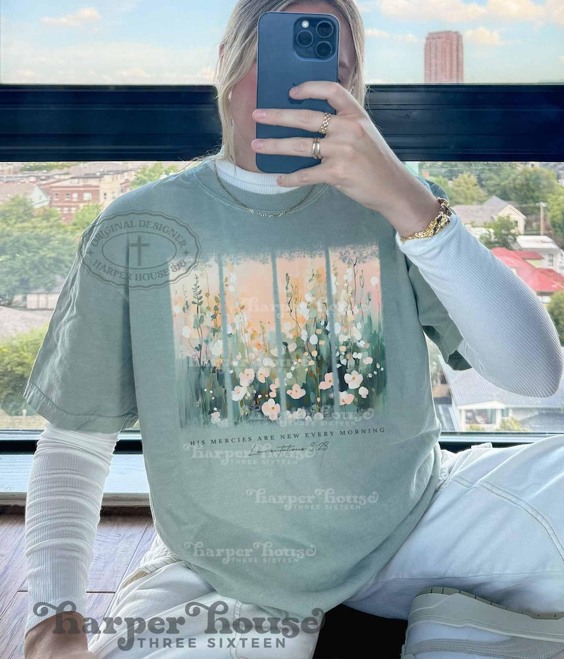 May include: A light green t-shirt with a floral design and the text "His mercies are new every morning" and a small text "Lamentations 3:23". The shirt has a distressed look and is made of a soft, comfortable material.