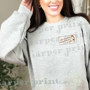 May include: A gray sweatshirt with a brown pocket featuring a phone graphic and the text "Can't wait to hear from you! So God"