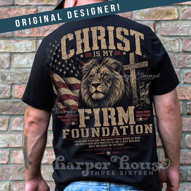 May include: Black t-shirt featuring a lion's head, American flag, and a cross. The text reads "CHRIST IS MY FIRM FOUNDATION" with a Bible verse. The shirt has a distressed, vintage look.
