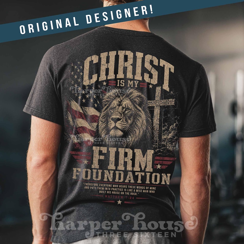 May include: Dark gray t-shirt featuring a lion's head, cross, and American flag graphic. Text includes "Christ is my Firm Foundation" and a Bible verse. The shirt is from Harper House.