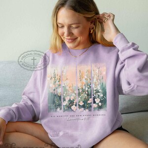 May include: A lavender sweatshirt with a floral design and the text "His mercies are new every morning" and a scripture reference. The sweatshirt has a cross and the text "Harper House 316" on the left sleeve.