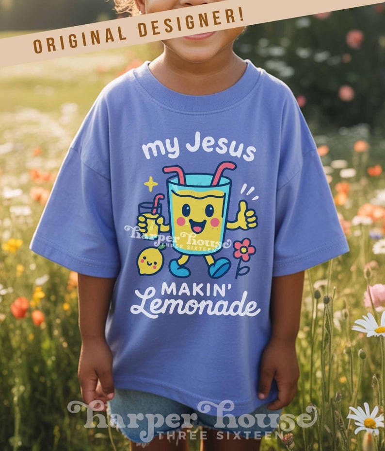 Op de afbeelding: Een lichtblauw t-shirt met de tekst "my Jesus makin' lemonade" en een cartoon limonade karakter. Het shirt heeft ook de tekst "ORIGINAL DESIGNER!" en de merknaam "Harper House Three Sixteen".
