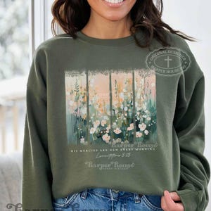 May include: A green sweatshirt with a floral design and the text "His mercies are new every morning" and "Lamentations 3:23". The sweatshirt also has the text "Harper House" and "Three Sixteen" on it.