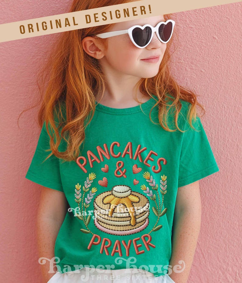 May include: A green t-shirt with the embroidered words "PANCAKES & PRAYER" in a playful font. The design includes a stack of pancakes with syrup, hearts, and floral accents. The shirt is worn by a person wearing heart-shaped sunglasses.