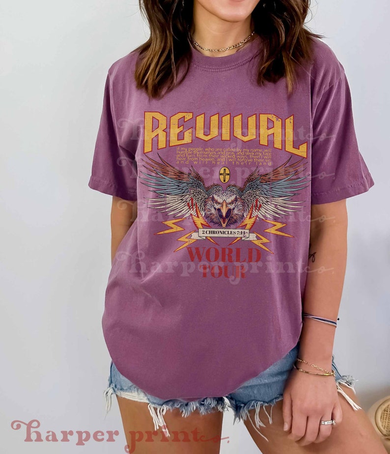 May include: Purple t-shirt with a graphic design of an eagle with wings spread, lightning bolts, and the text "REVIVAL 2 CHRONICLES 7:14 WORLD TOUR".