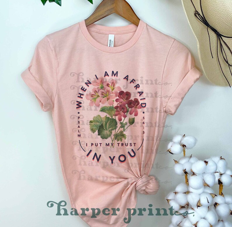 May include: A pink t-shirt with a floral design and the text "WHEN I AM AFRAID *PSALM 56:3* I PUT MY TRUST IN YOU".